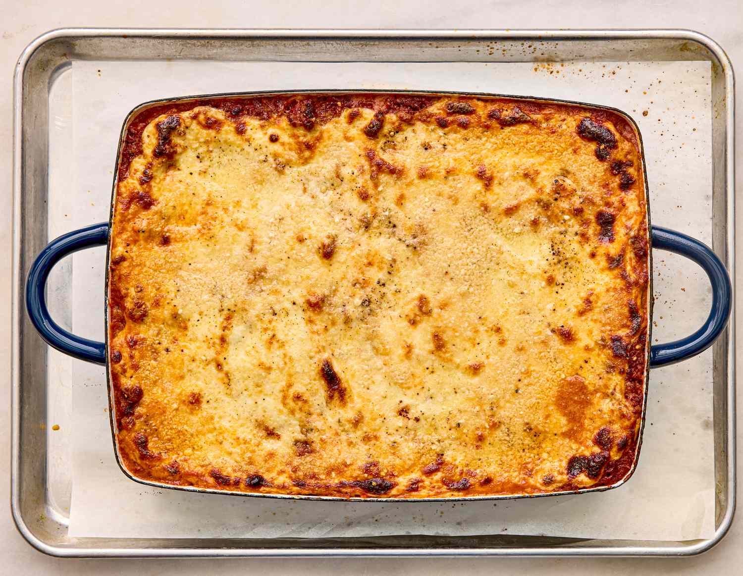 A baked casserole dish resting on a baking tray showing golden crust indicating completion