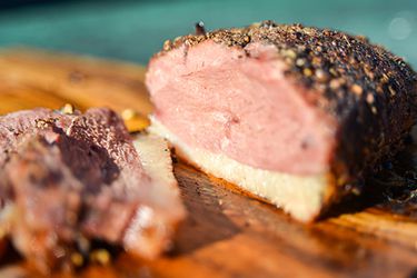 Closeup of a sliced duck breast pastrami on a wooden cutting board