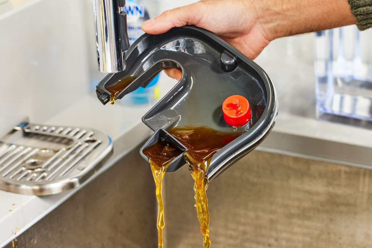 Hand pouring out coffee from Breville Bambino Plus Espresso Machine tray