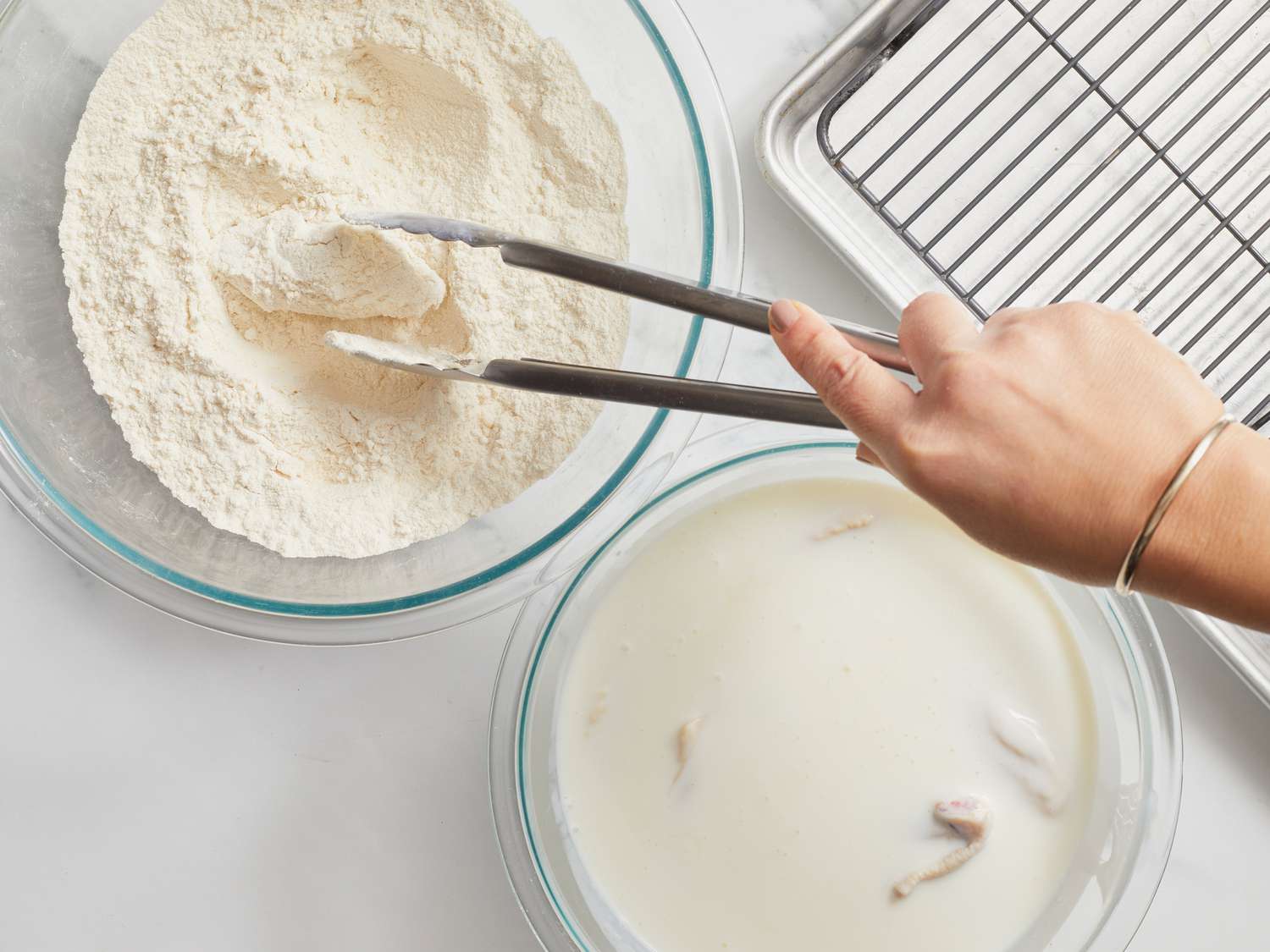 Dredging chicken in flour with tongs 