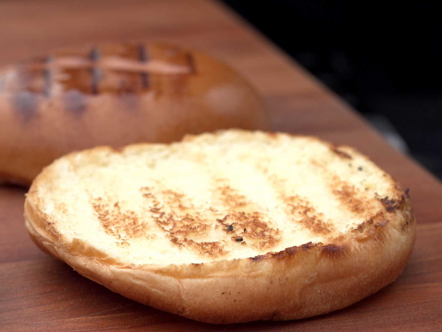 A top and bottom of a burger bun that has grill marks on them