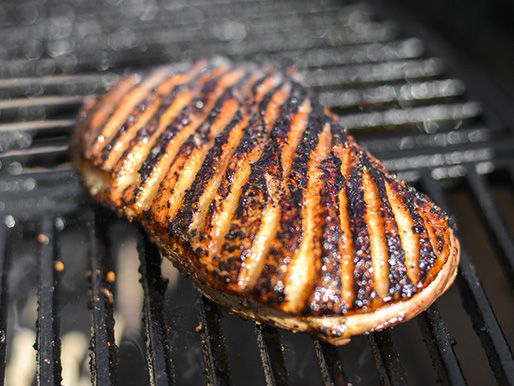 The scored duck breast is browned on a grill.