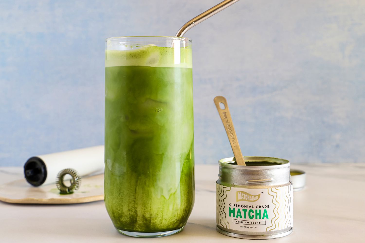 A glass of Matcha Bar Premium Blend next to the container