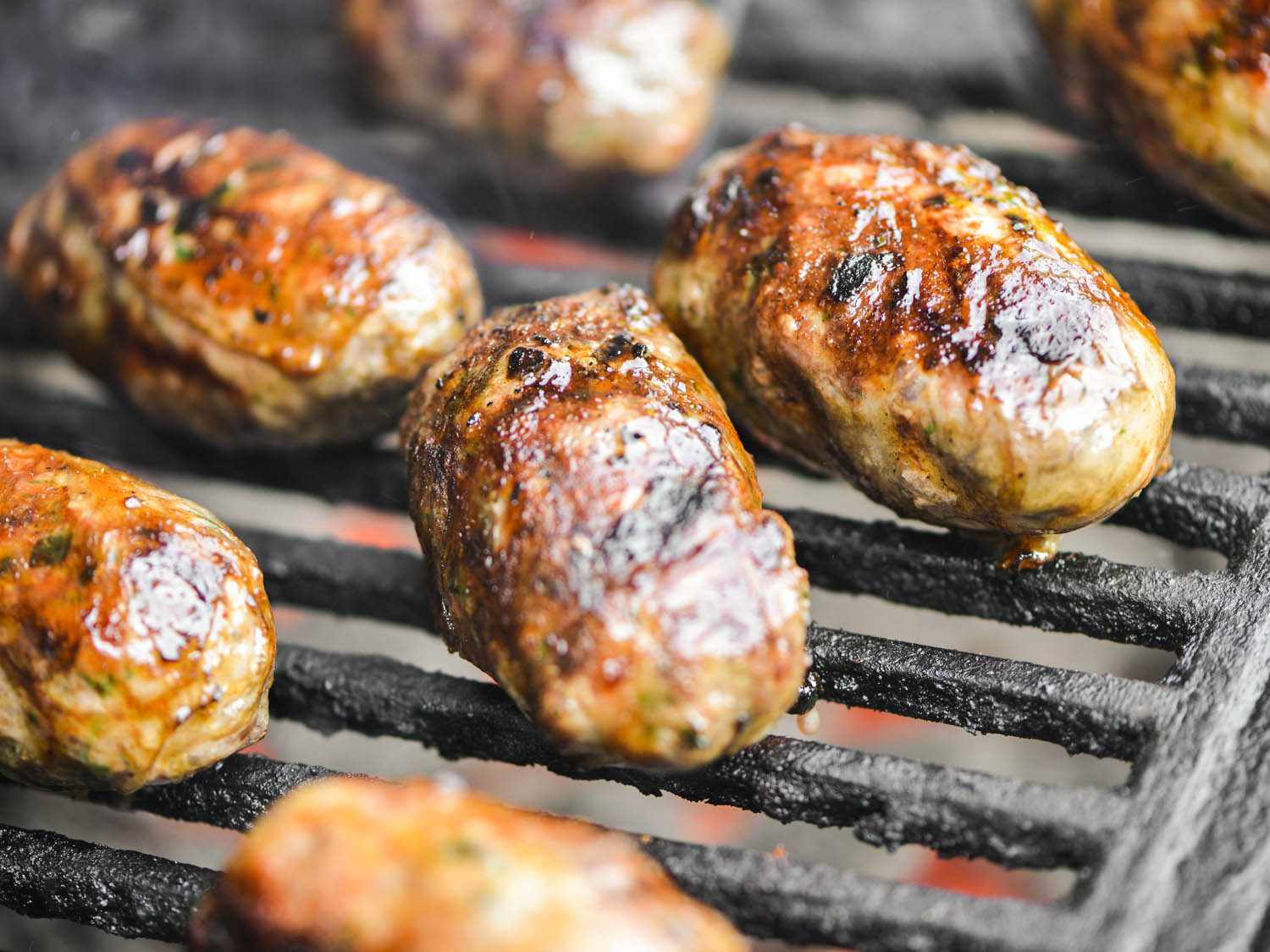 Sheftalia sausages browning on the grill.