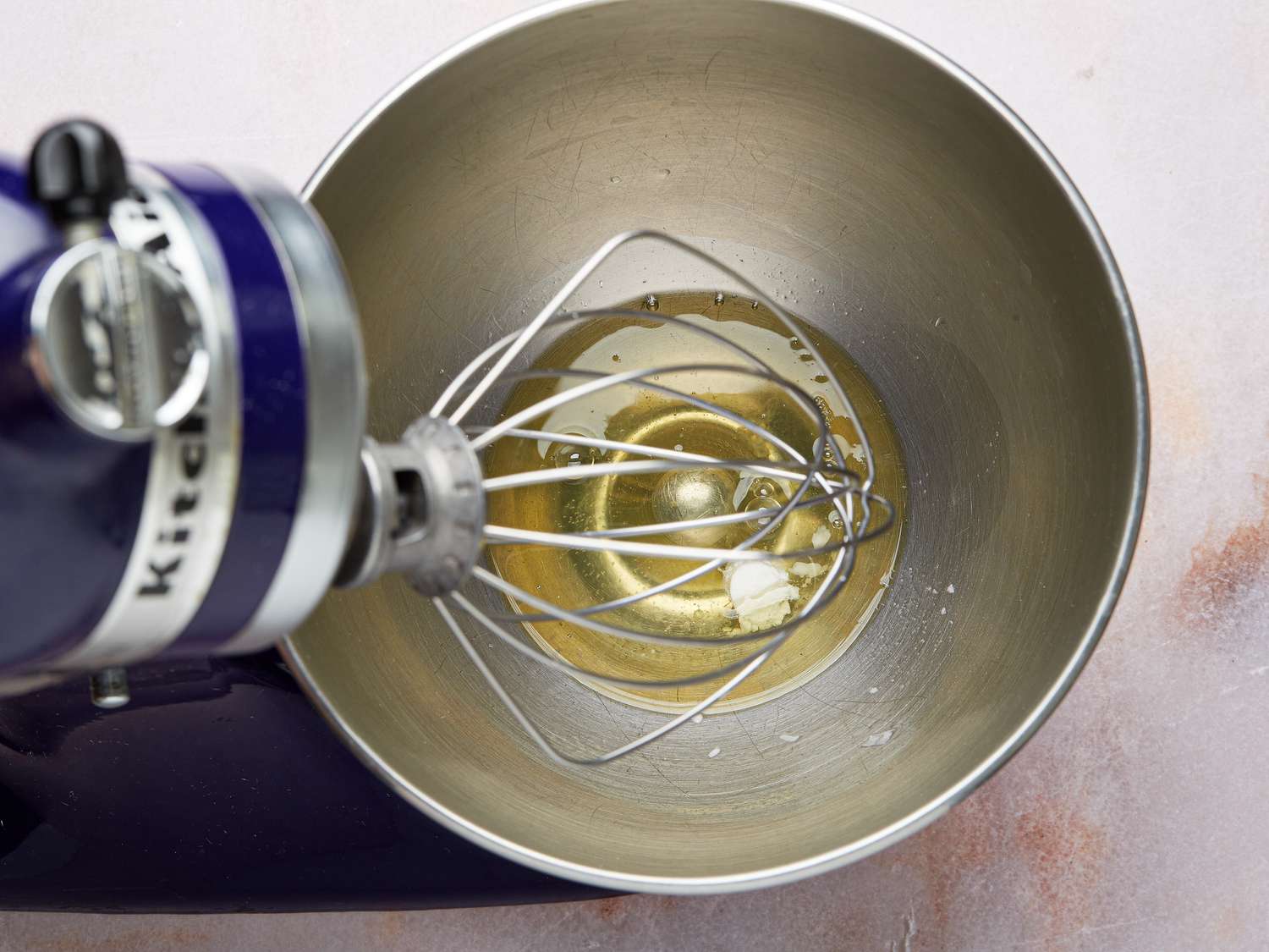Whisking egg whites and cream of tartar in a bowl of a stand mixer with a whisk attachment 