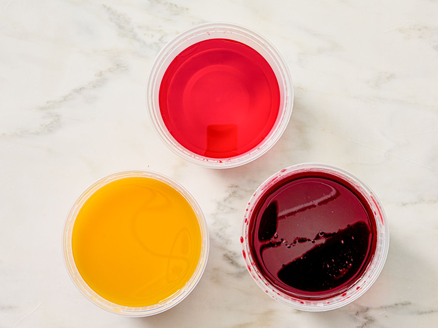 Three cups containing liquids of different colors viewed from above