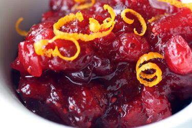 Cranberry chutney in a bowl topped with curls of shaved orange zest.