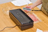A person measures the sound emitted from the Anova Precision Vacuum Sealer Pro while in use