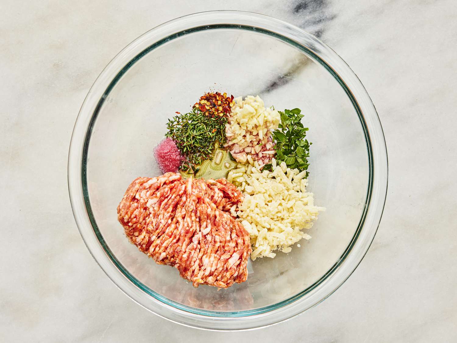 Suasage, wine, thyme, garlic, oregano, salt, parmesan, and red pepper in a glass bowl 