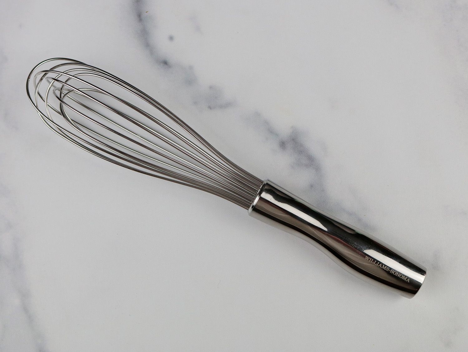 a small french whisk on a marble surface