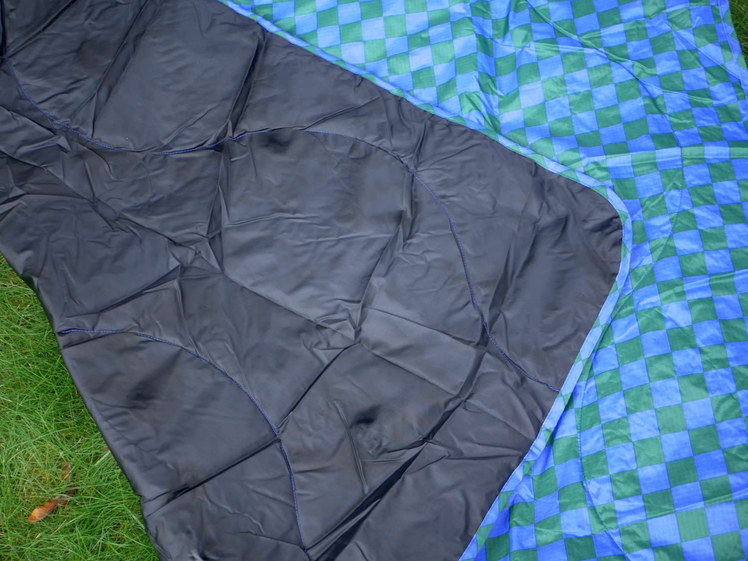 the baggu blanket on grass with a corner folded over to show the wet splotches on the bottom