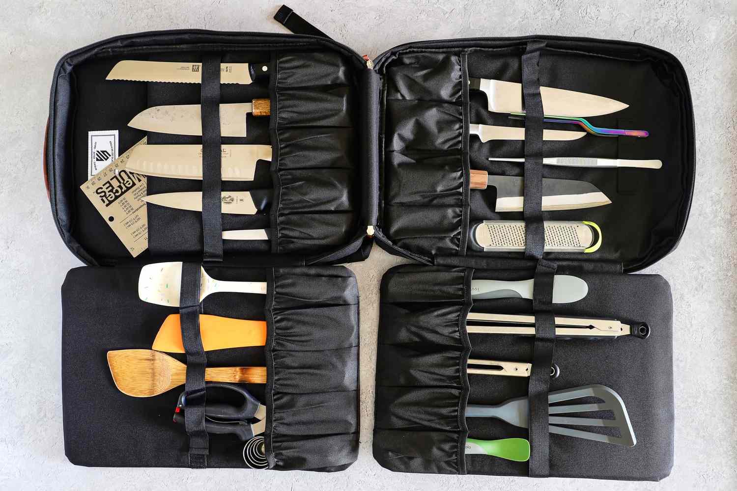 A black knife and kitchen utensil storage case with various knives and tools securely stored inside
