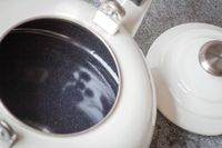 An open enamelkitchen kettle with a removed lid showing its interior