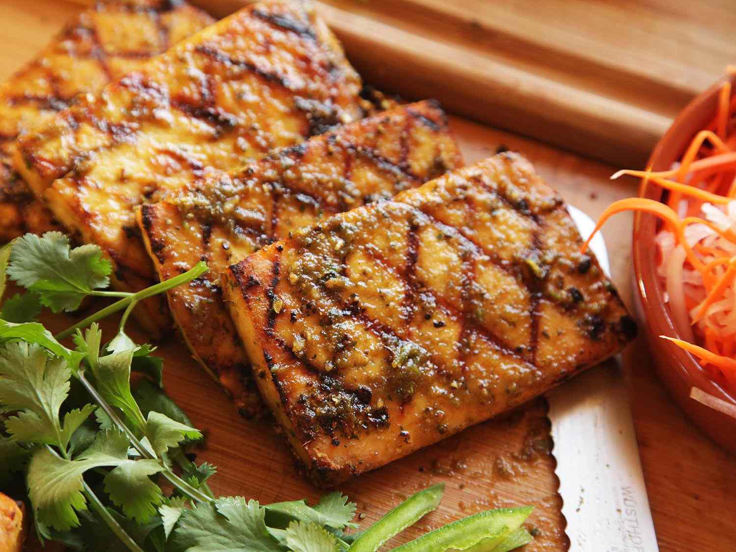 Char-marked marinated tofu slices of wooden board