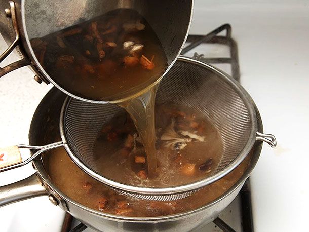 Mushroom-infused stock is strained into the saucepan.