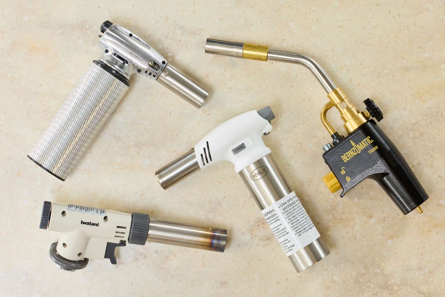 four kitchen torches on a beige surface