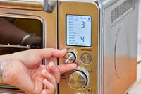 A hand moving a small nob on the Breville the Smart Oven Air Fryer