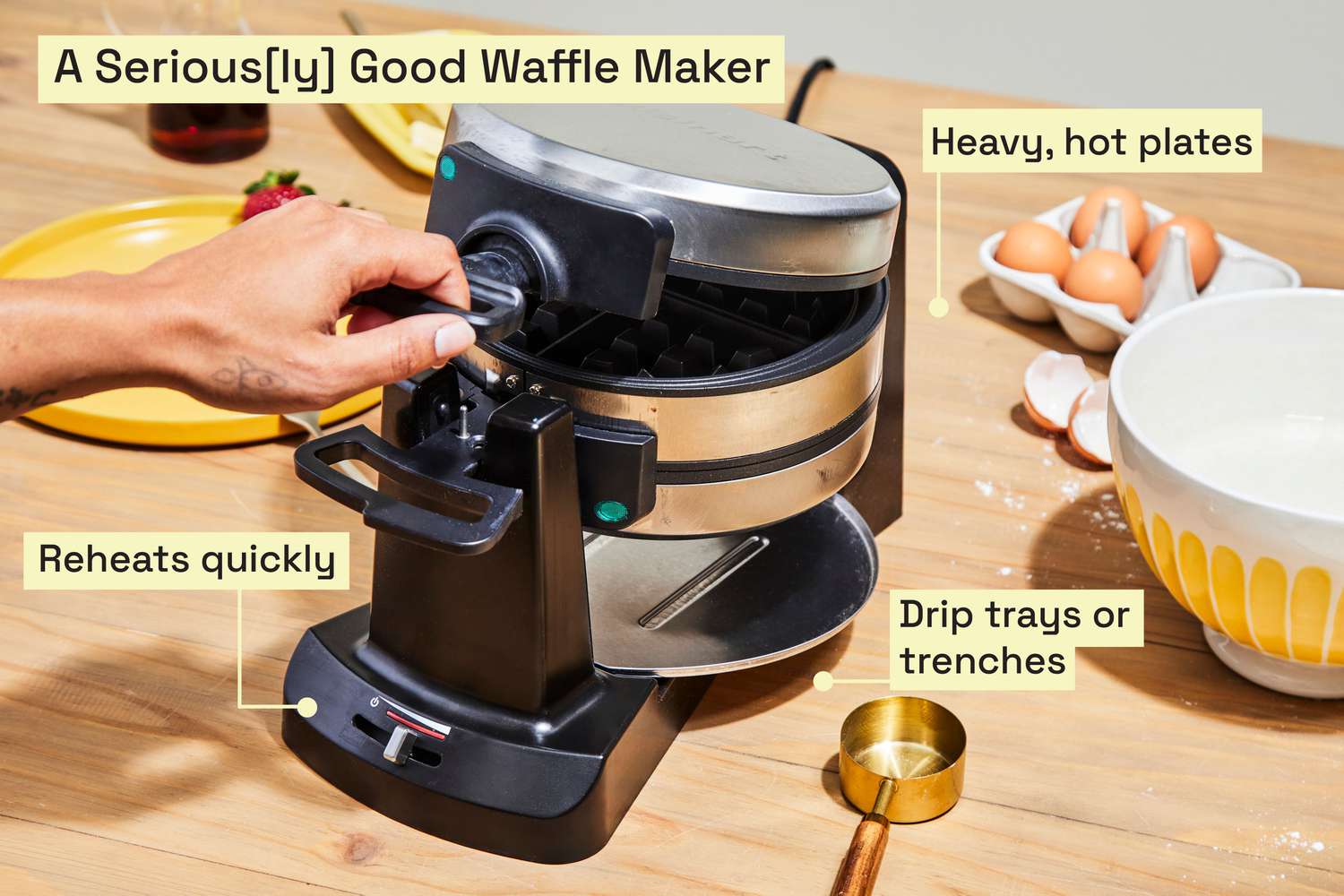 A stainless steel waffle maker on a cluttered kitchen countertop