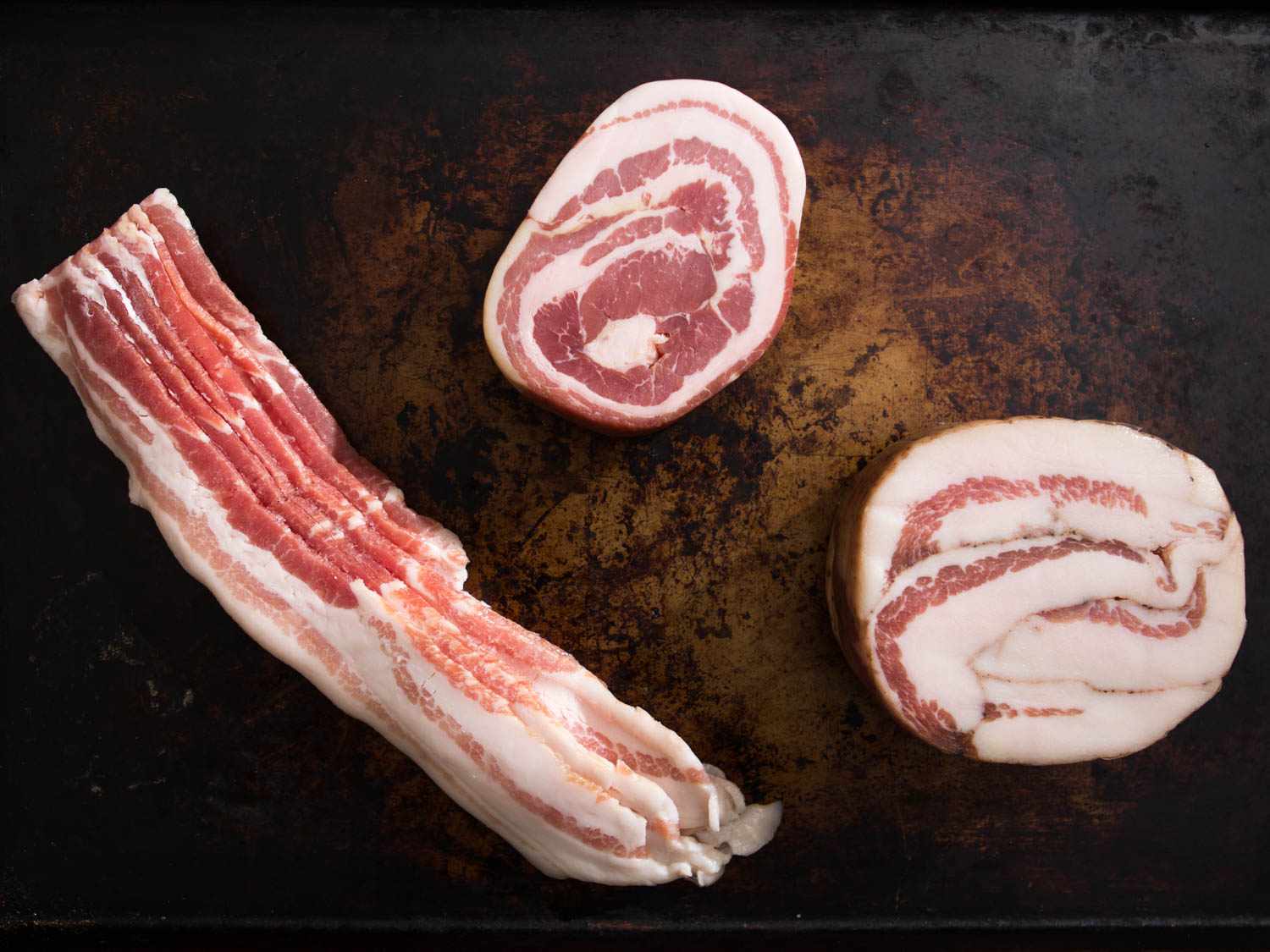 Overhead shot of sliced bacon, guanciale, and pancetta.