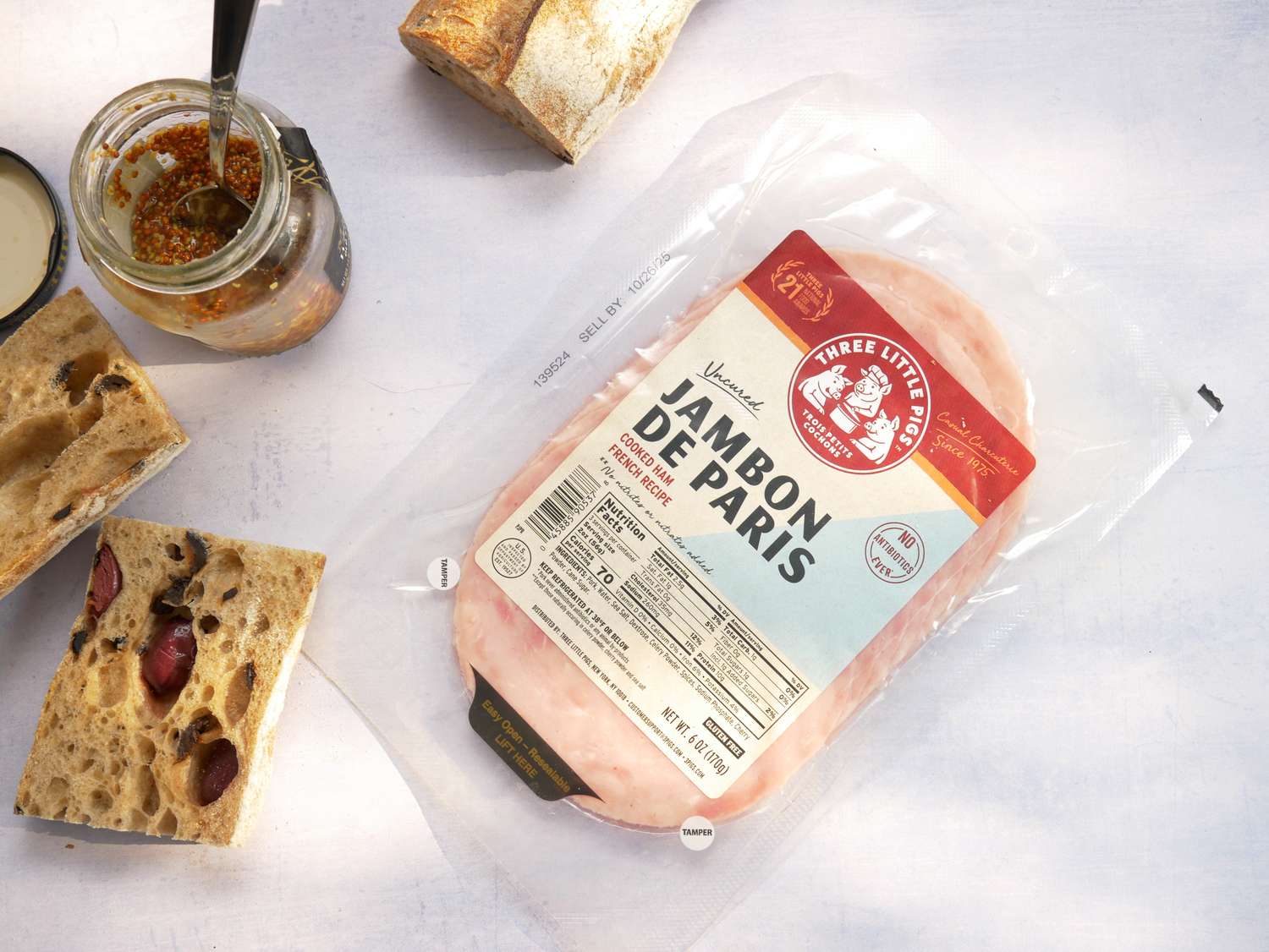 ham in a package on a blue surface with bread and mustard