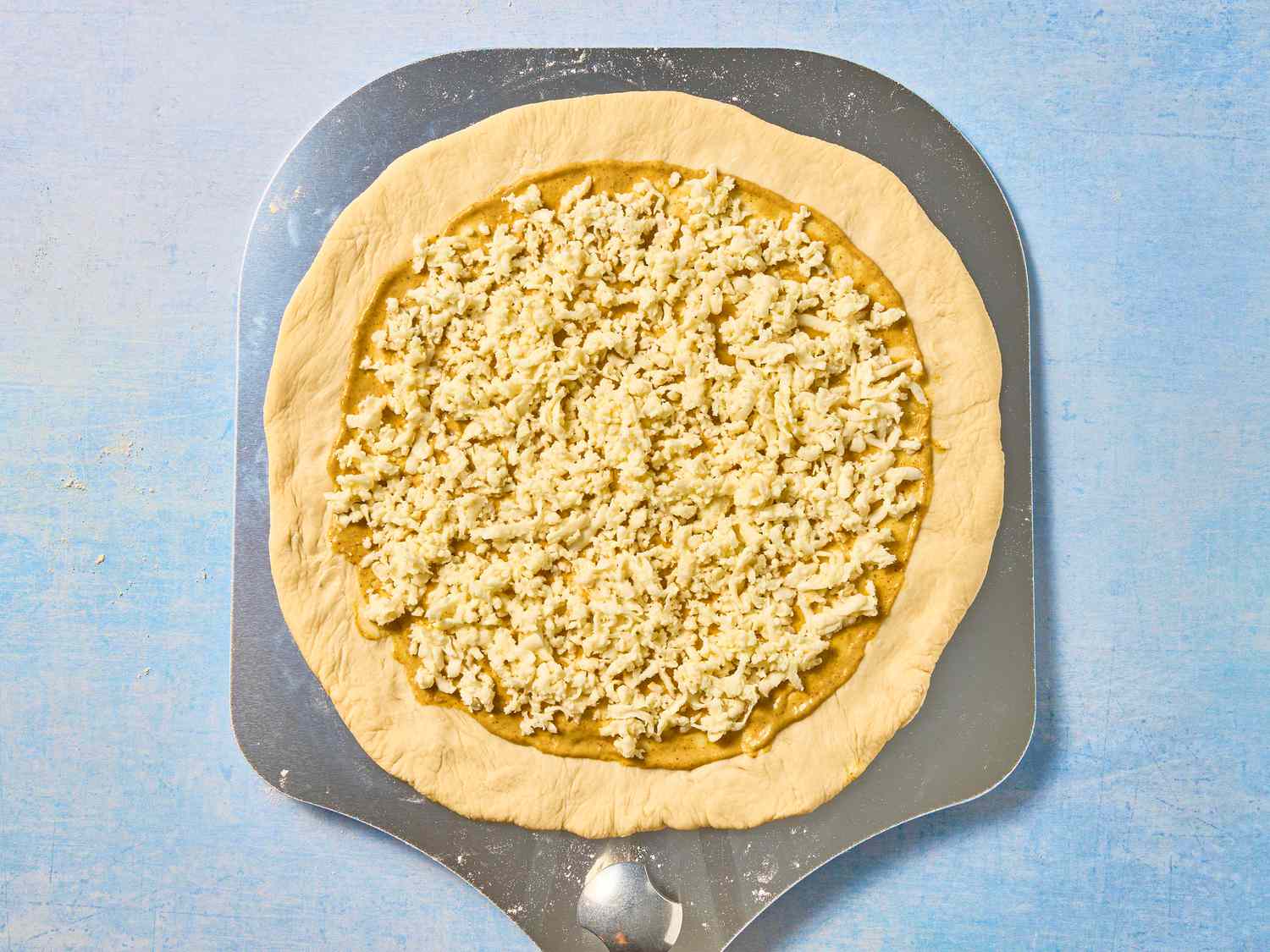Spreading cheese over the pizza dough 