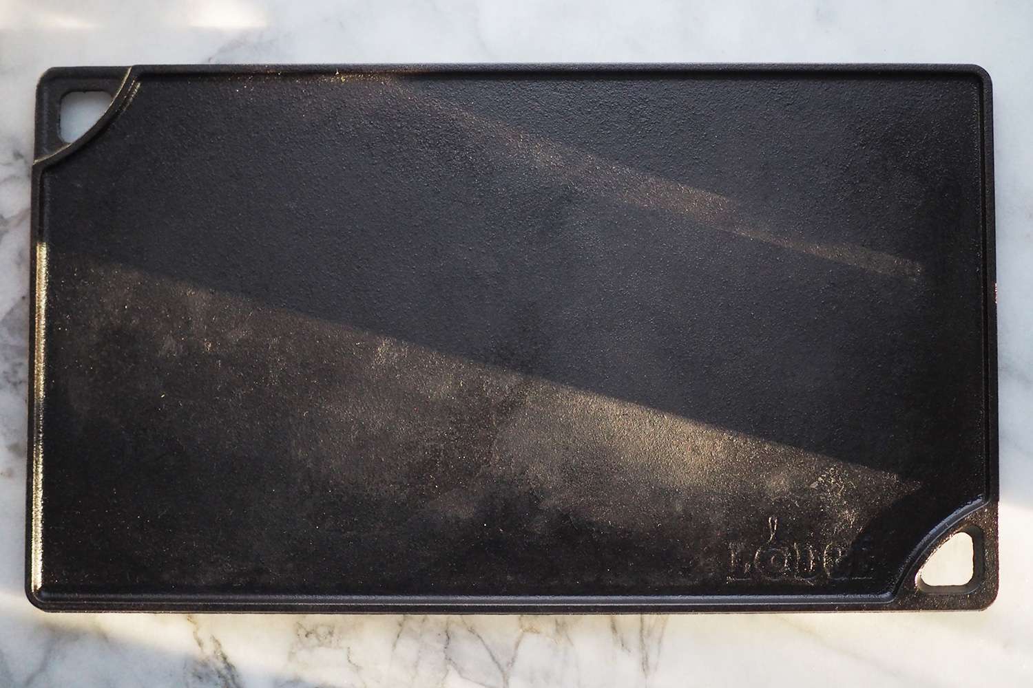 Lodge Reversible griddle laying on top of granite counter top in the sun light