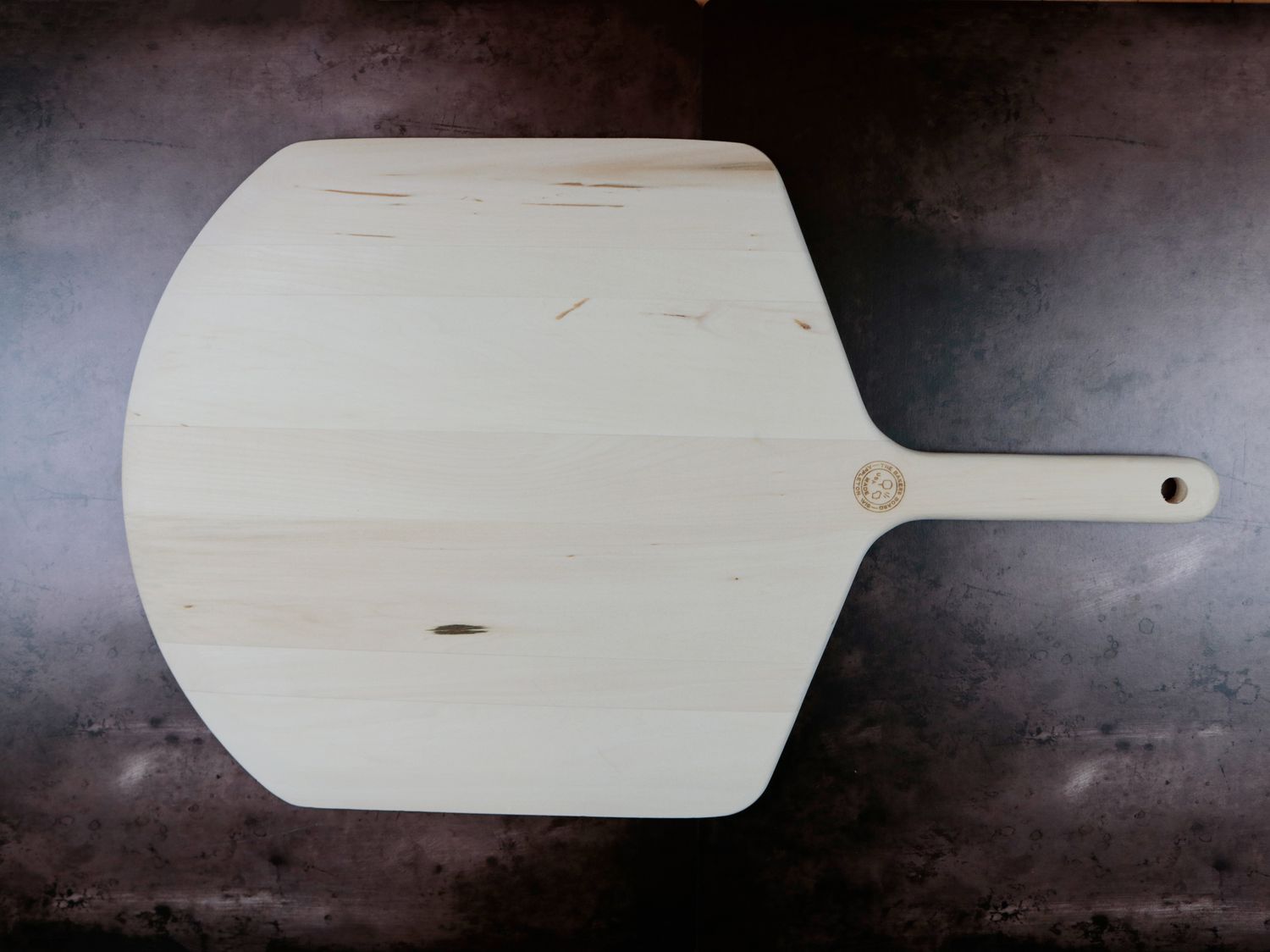 A wooden pizza peel on a dark background