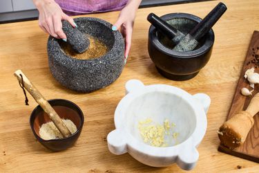 Four different types of mortar and pestles on a wooden countertop.