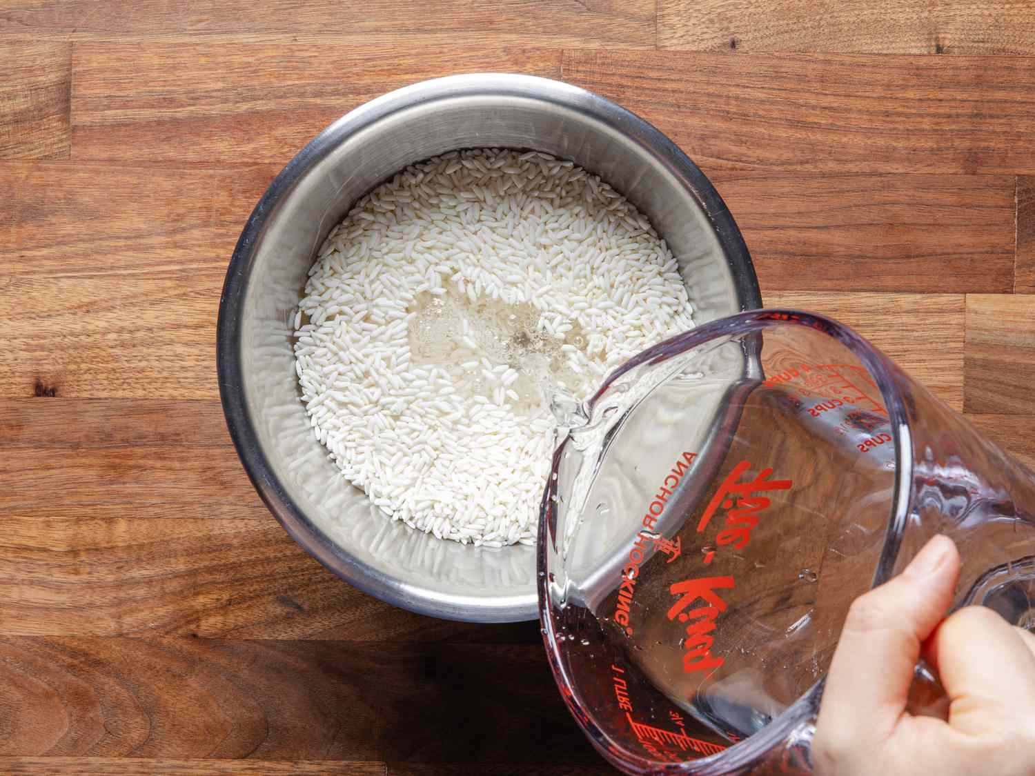 Overhead view of pouring water into a bowl of rice
