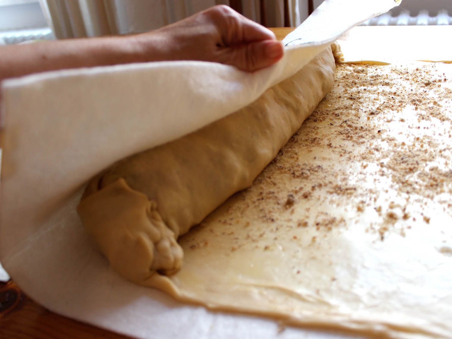 The strudel is rolled with the aid of the cloth underneath.