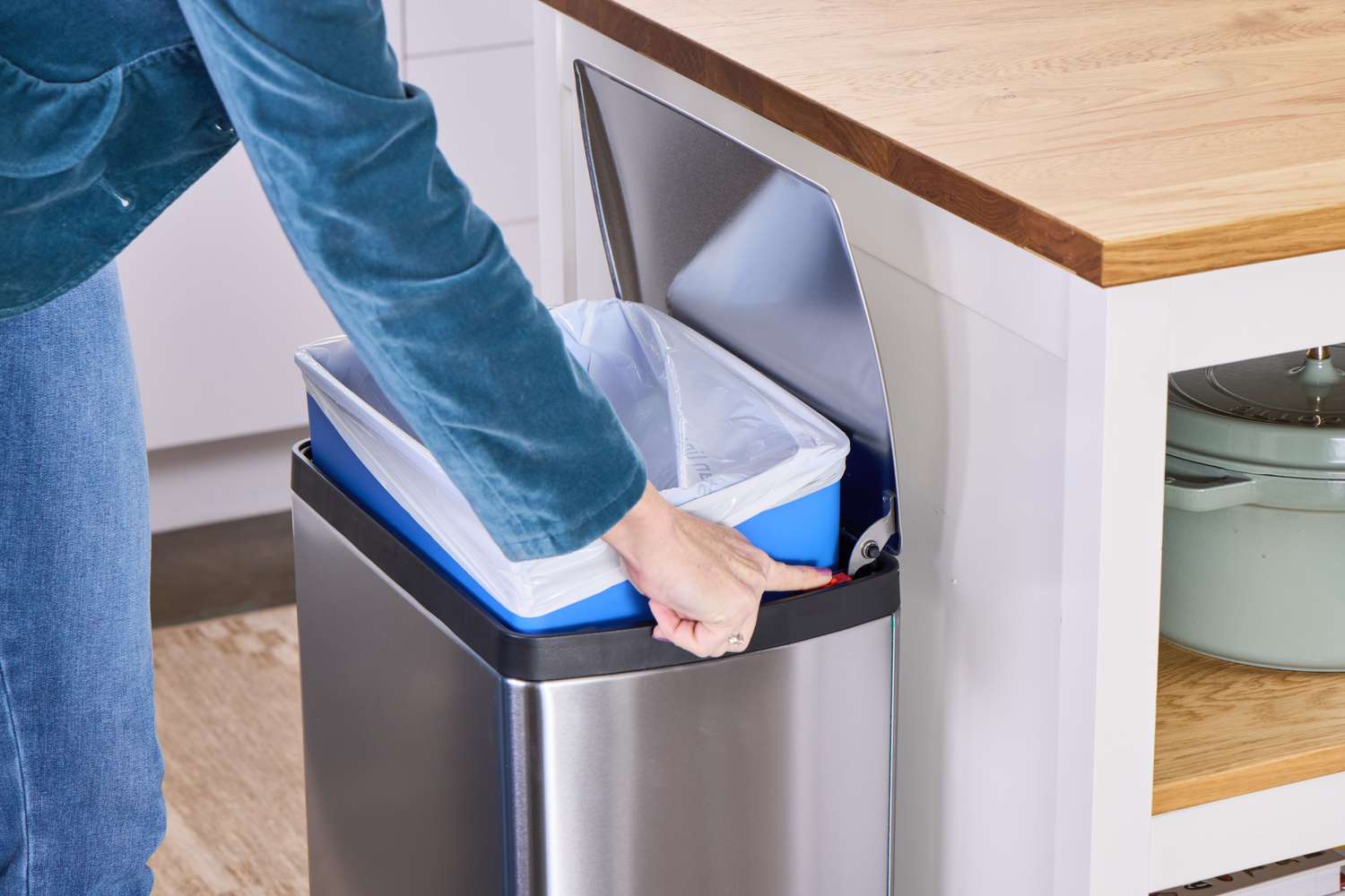 A person places an inner can into the simplehuman 38-Liter Brushed Stainless Steel Steel Trash Can with Lid