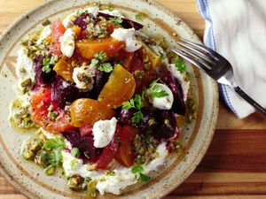 An overhead view of a colorful plate of beet and citrus salad with a pistachio dressing. 