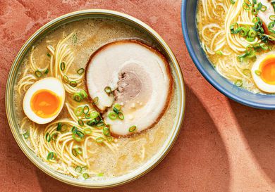 A bowl of homemade tonkatsu ramen topped with a marinated egg which has been sliced in half, and a slice of pork chashu.
