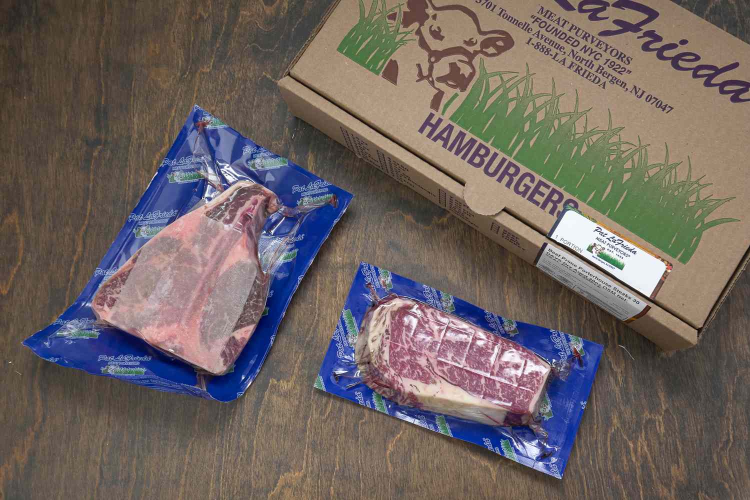 Packaged cuts of meat next to a LaFrieda box on a wooden table