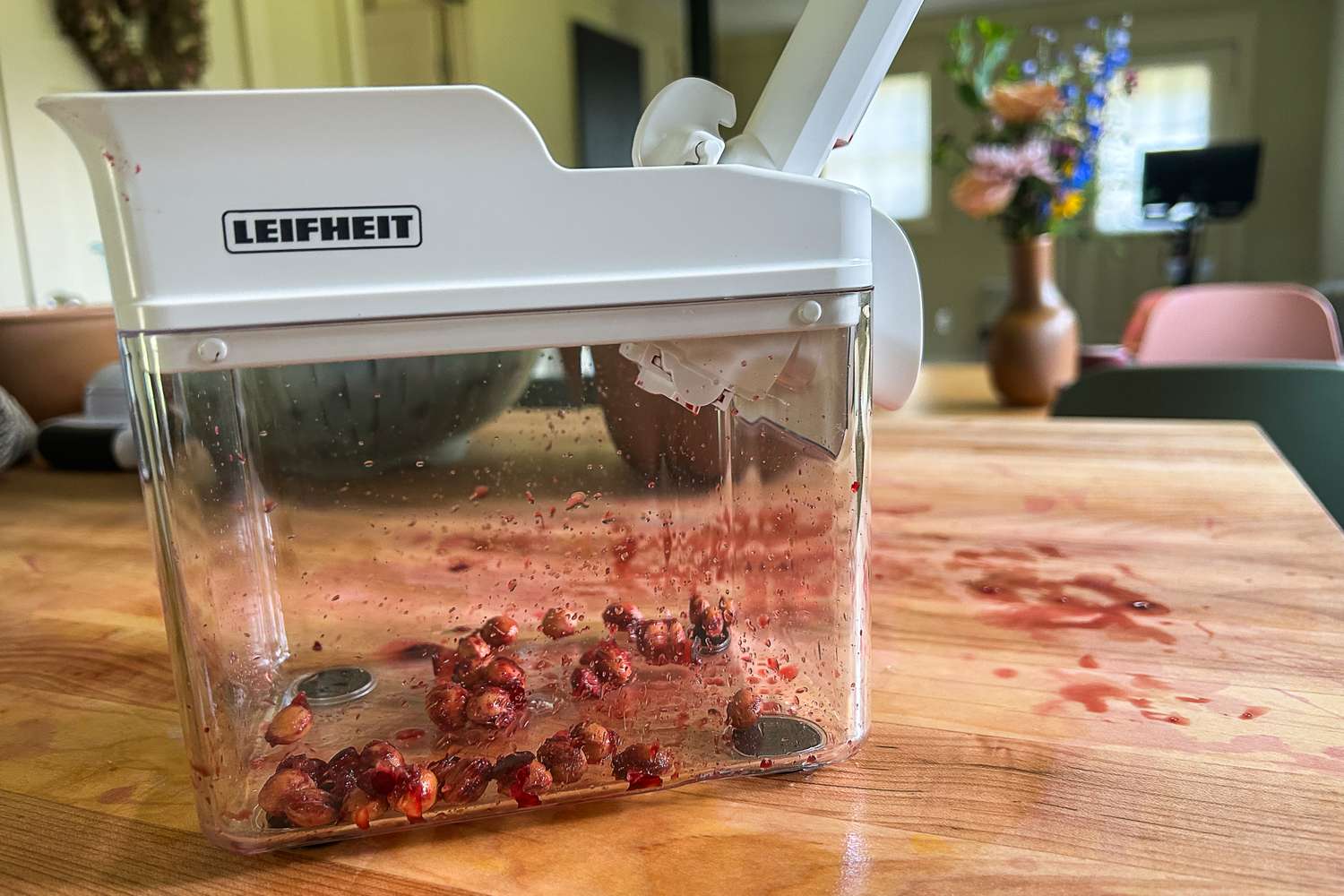 A closeup of the Leifheit cherry pitter with cherry pits in the bottom