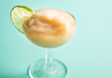 Frozen daiquiri in a coupe glass garnished with a lime wheel.