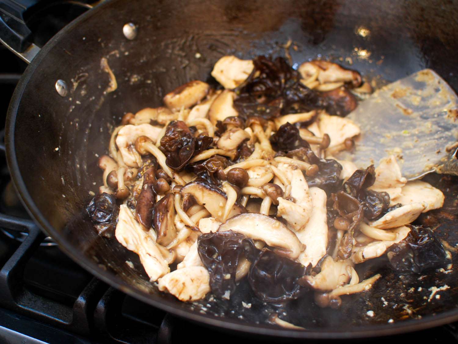 The chicken is added back to the wok and the ingredients are stir-fried together to finish.