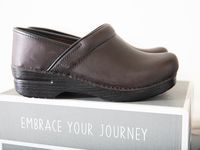 Brown Dansko kitchen clogs on top of a shoe box.