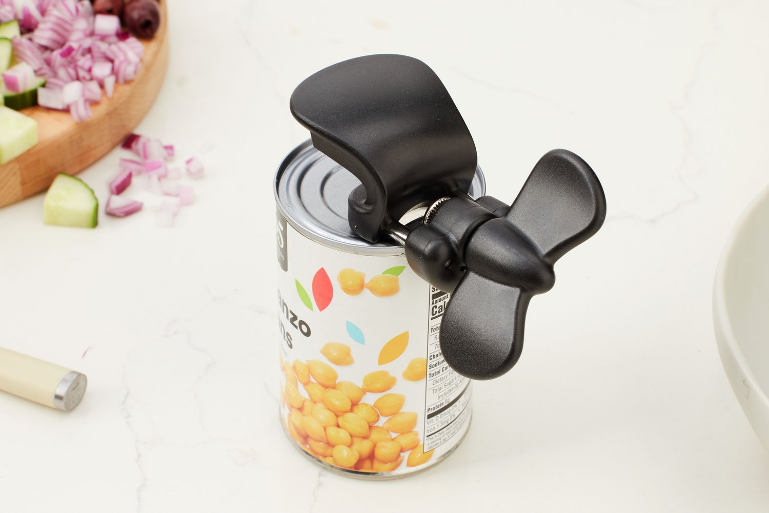A can opener being used to open a can of chickpeas