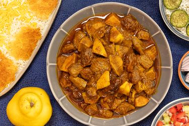 A dish of khoreshe beh alongside sides like rice and other accompaniments