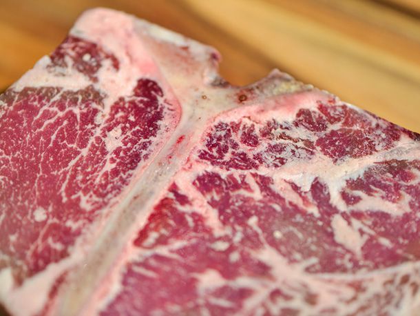 Close-up of the T-bone. The camera's focus depth emphasizes its ample marbling.