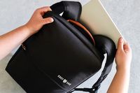 Hands placing a tablet into a black backpack branded Chef Sac