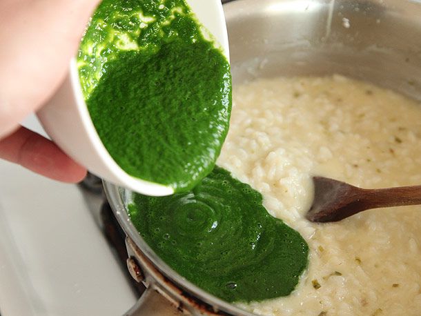 Green ramp purée being added to the pot of cooking risotto.