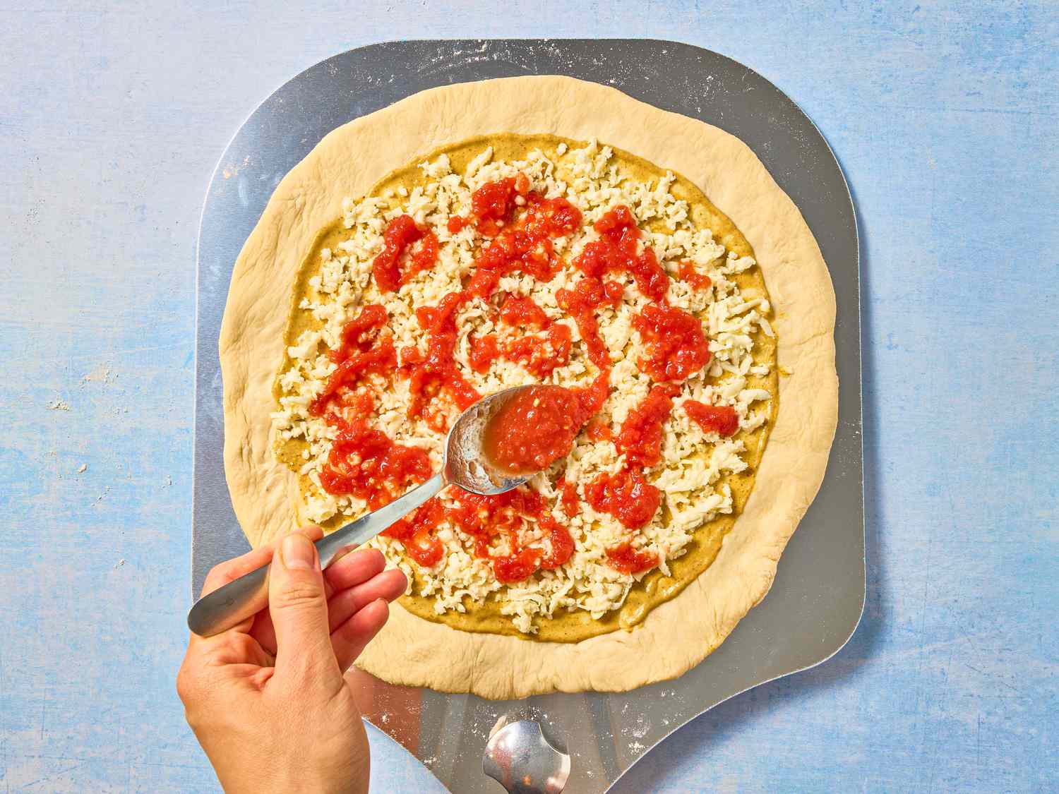 drizzling red cause over pizza dough 