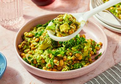 A bowl of broccoli and chickpea salad with a spoon serving a portion