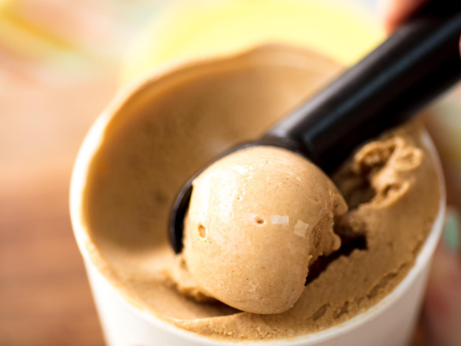 Scooping homemade speculoos ice cream out of a pint container.