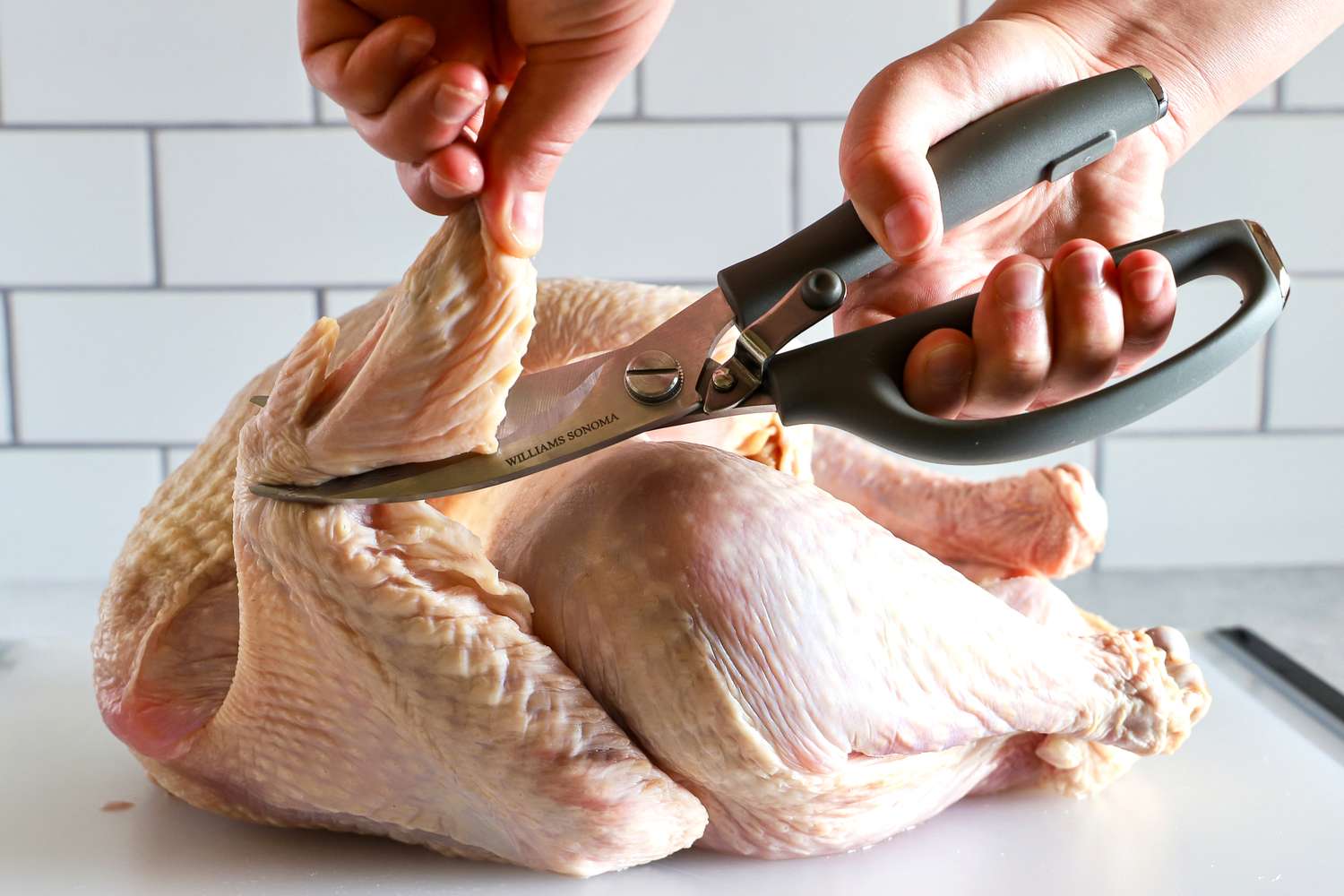 Hands using Williams Sonoma poultry shears to cut a turkey wing
