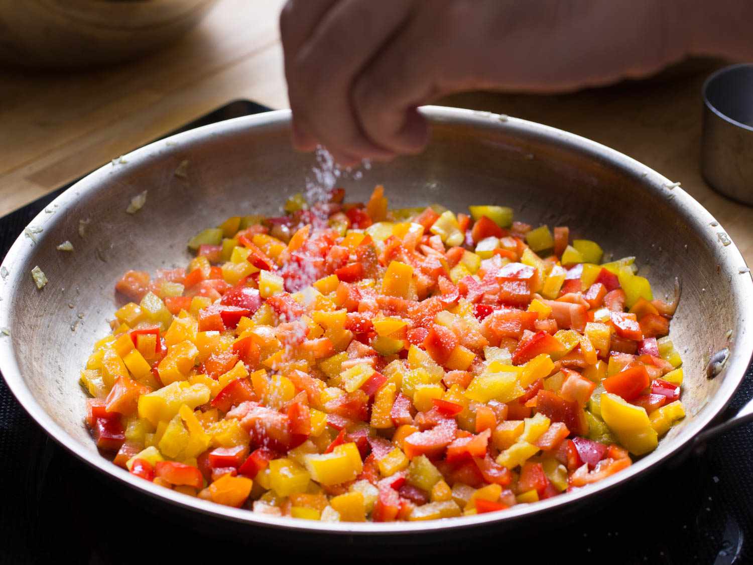 Author sprinkling salt over diced bell pepper as it cooks.