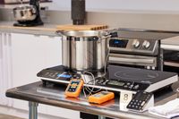 A stockpot sits on The Duxtop Portable Double Induction Cooktop. An instant-read thermometer is monitoring the temperature of water.