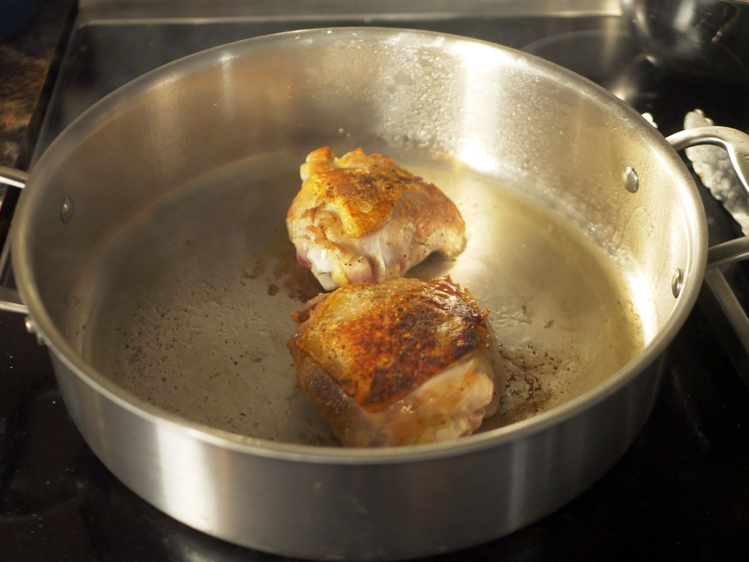 Two seared chicken thighs in the center of the Made In rondeau